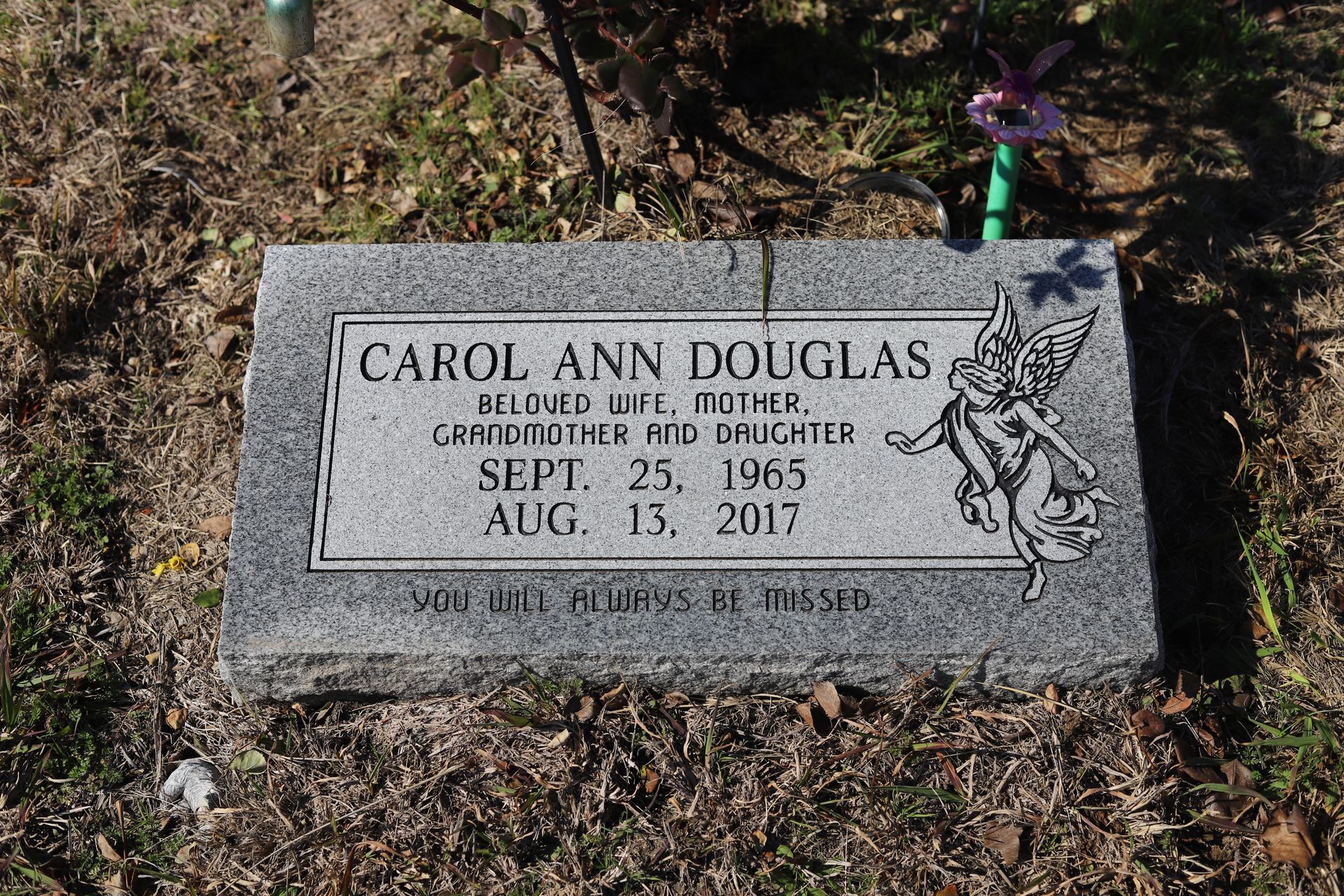 Gray headstone of Carol Ann Douglas, with birth and death dates, and a decorative angel.