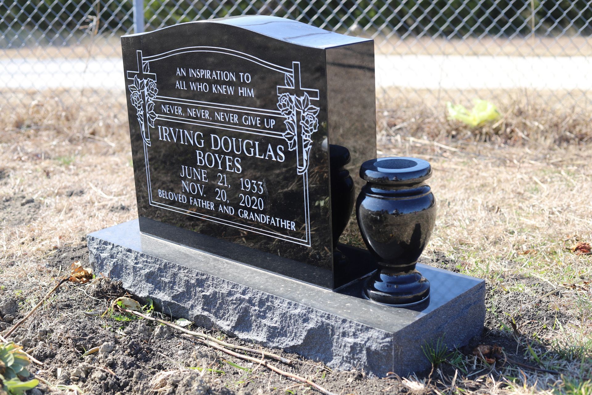 Black granite headstone with vase, outdoors. Inscriptions name Irving Douglas Boyes, birth and death dates.