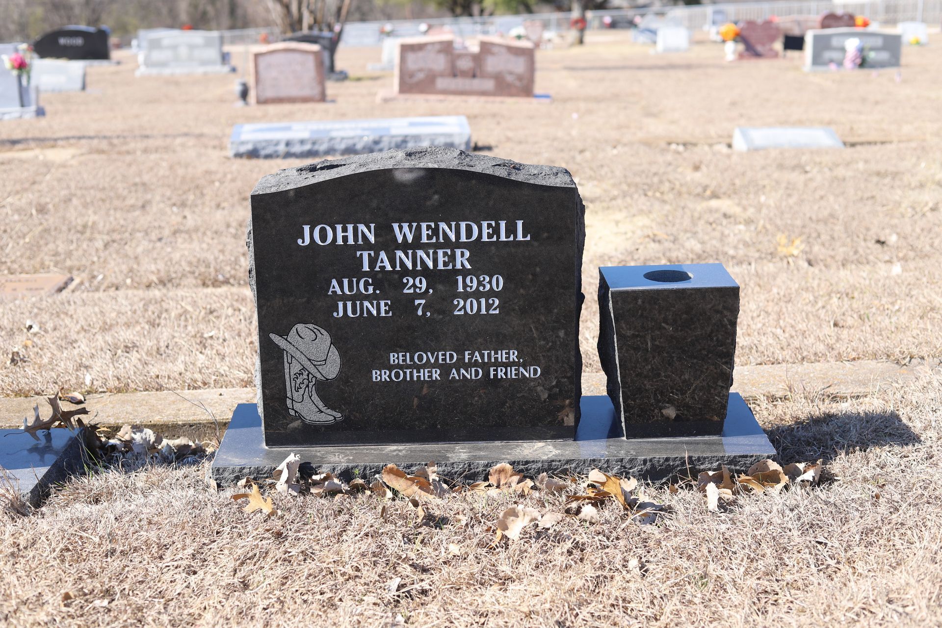 Black headstone in a cemetery reads