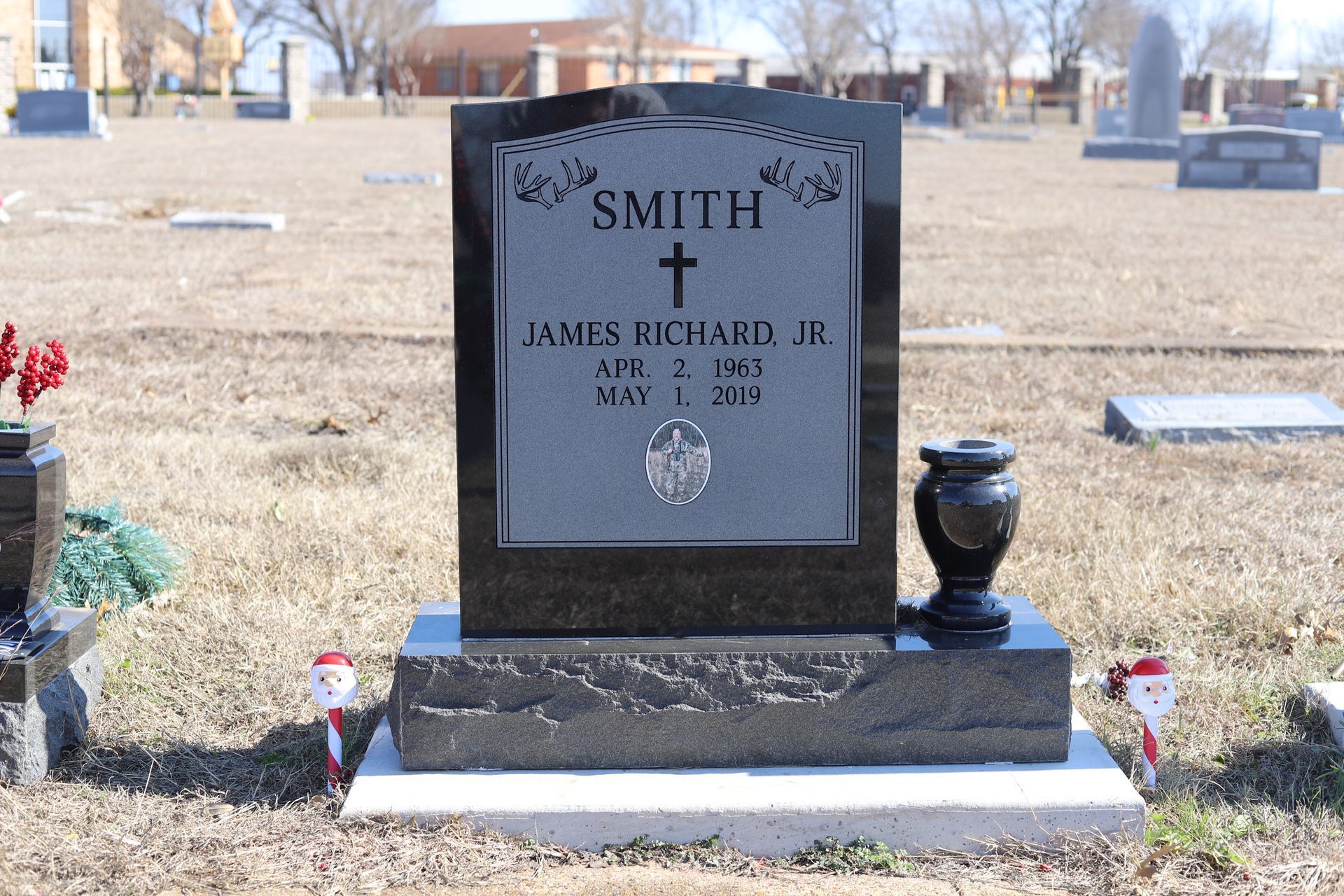 Grave marker in a cemetery with a black headstone, name
