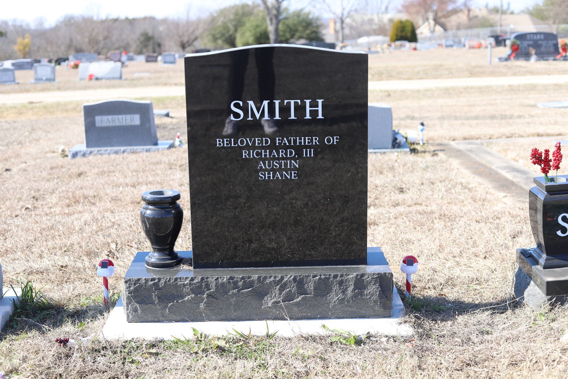 Black granite headstone in a cemetery; reads