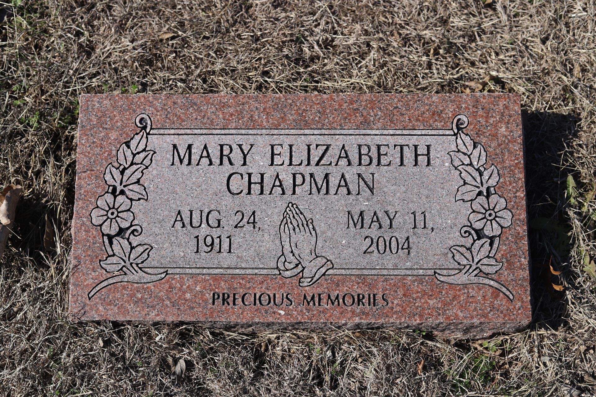 Headstone of Mary Elizabeth Chapman, born 1911, died 2004, with praying hands and floral border.