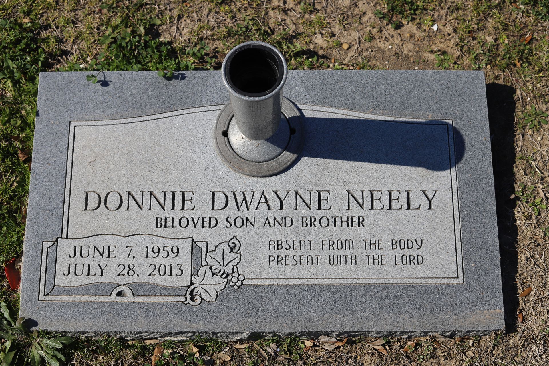 Headstone of Donnie Dwayne Neely with birth/death dates, a vase, and a floral emblem.