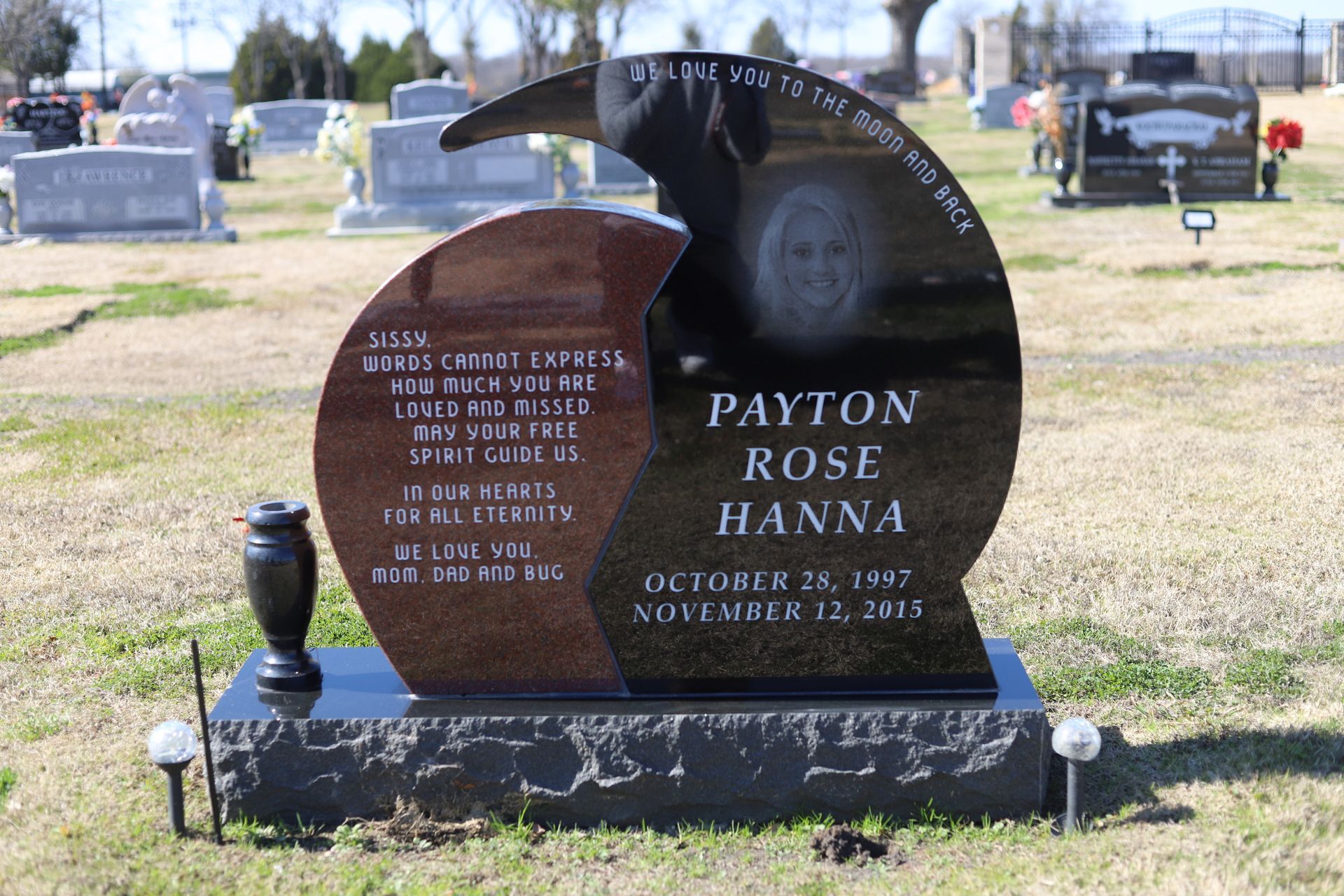 Headstone for Payton Rose Hanna at a cemetery. Dark granite with a photo, birth/death dates.
