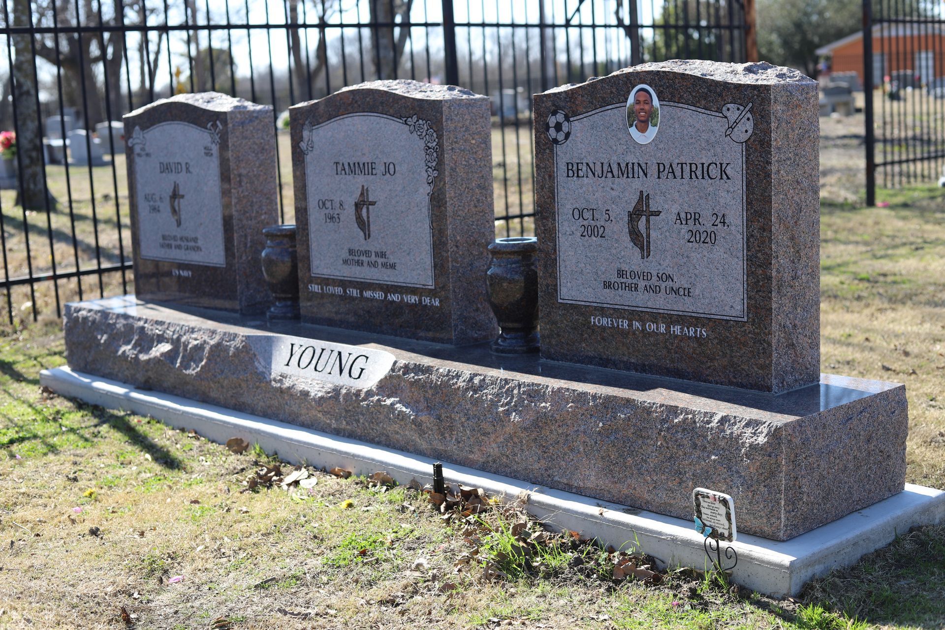Three granite headstones in a cemetery with a shared base, 