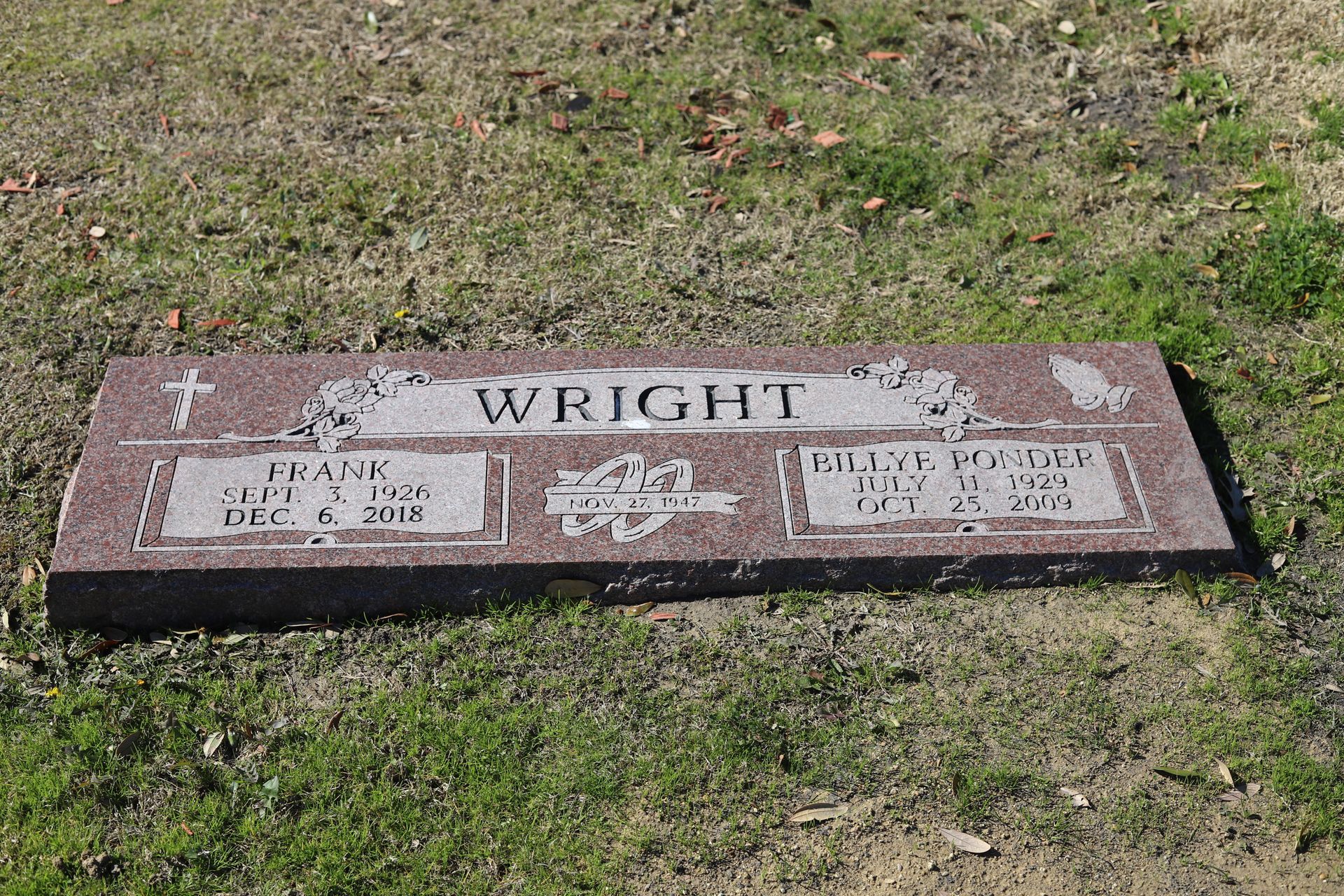 Red granite headstone for the Wright family in a grassy field. Dates of birth and death are inscribed.