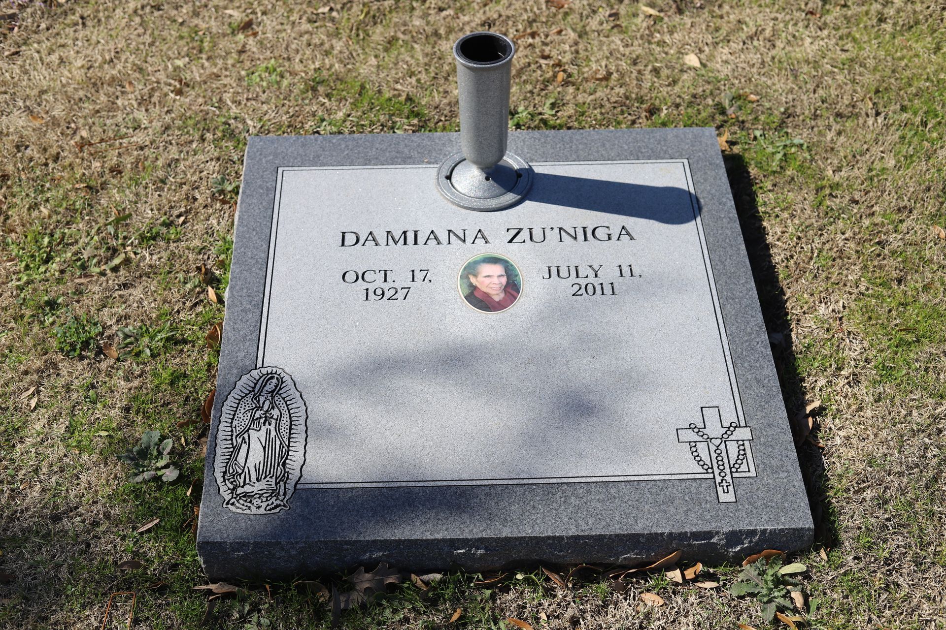 Headstone of Damiana Zuniga, with a photo, dates of birth and death, and a vase.