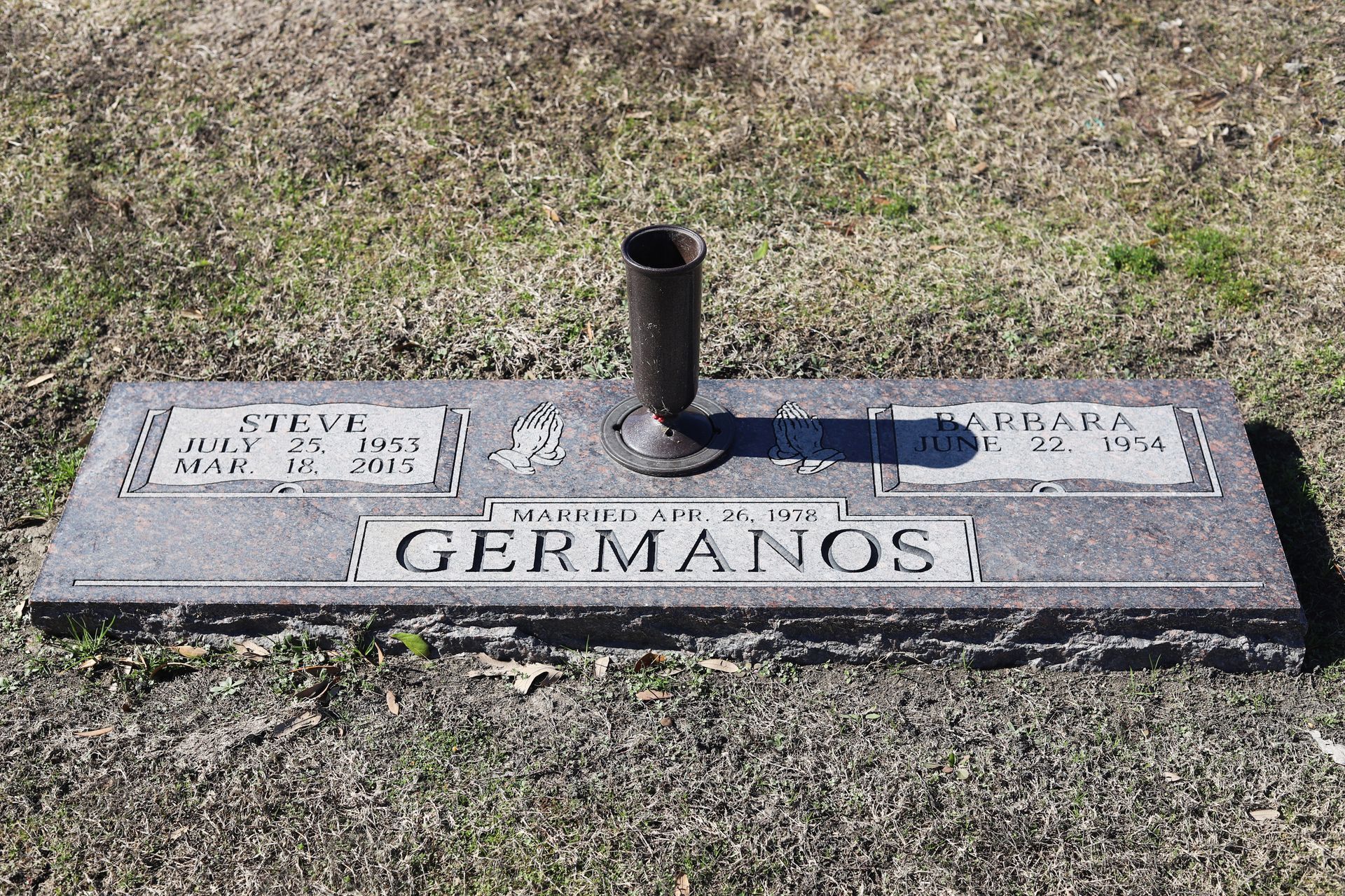 Gravestone with the surname GERMANOS and names, birth and death dates, and a vase.