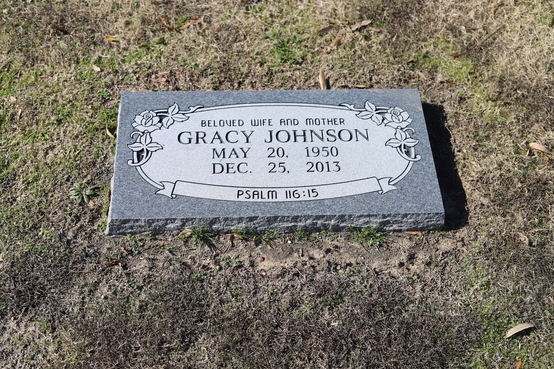 Gray headstone in grass reads 