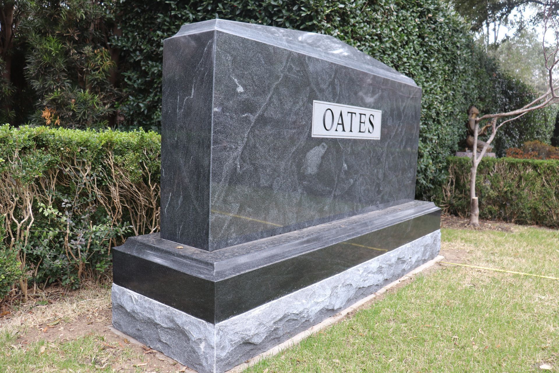 Dark granite OATES headstone in a grassy cemetery.