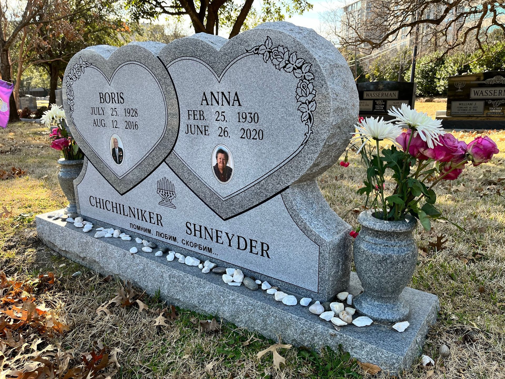 Heart-shaped granite headstone in a cemetery with names, dates, and photos of loved ones.