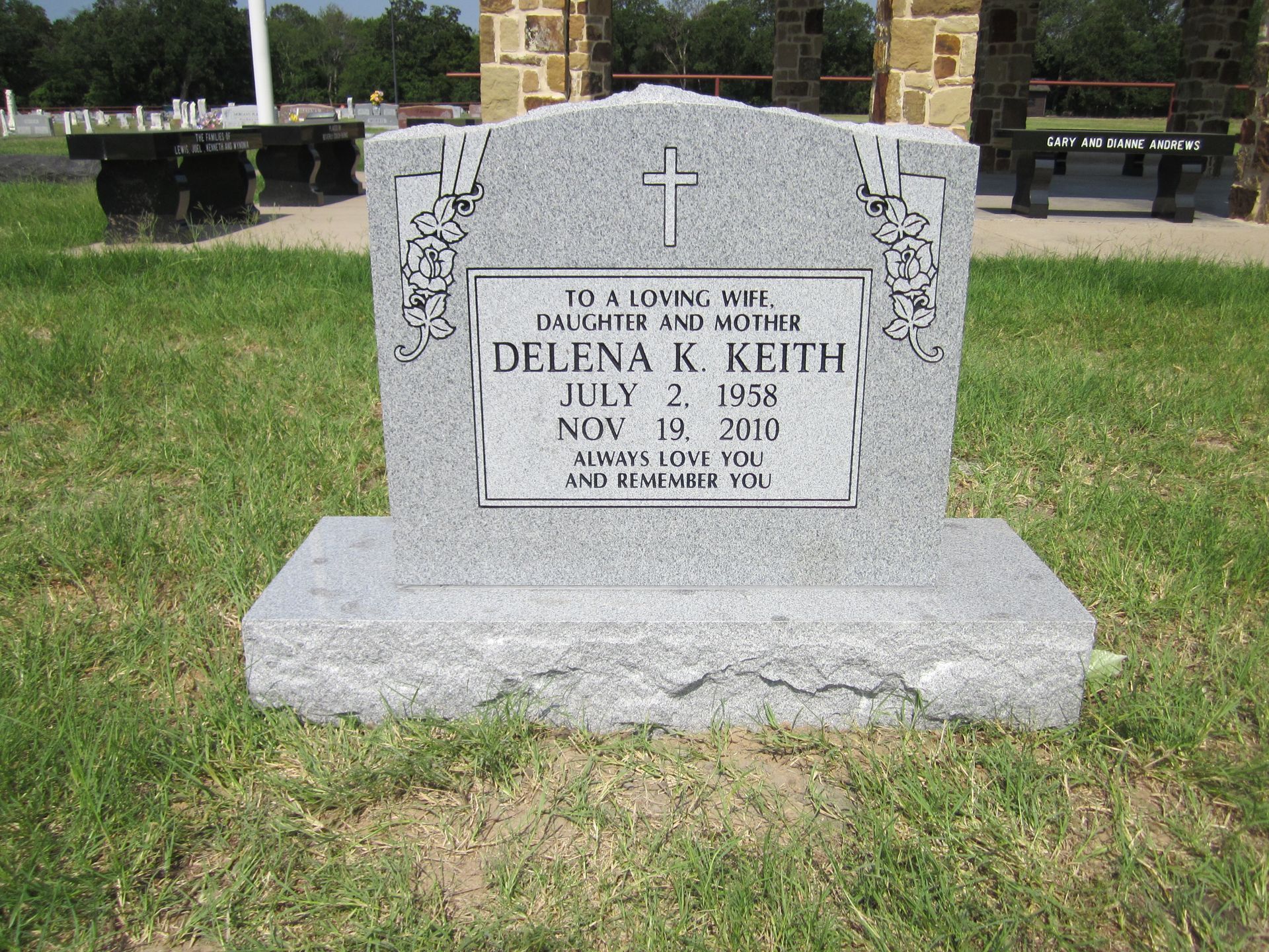 Gravestone of Delena K. Keith, with a cross, dates of birth and death, set in a grassy cemetery.