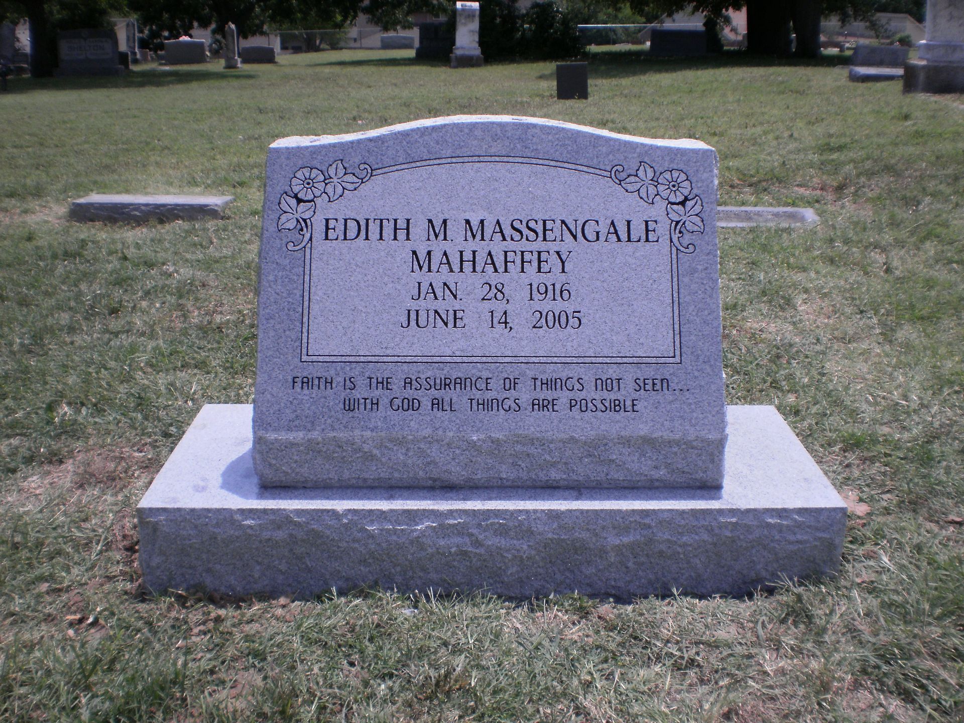 Gray headstone in a grassy cemetery, inscribed