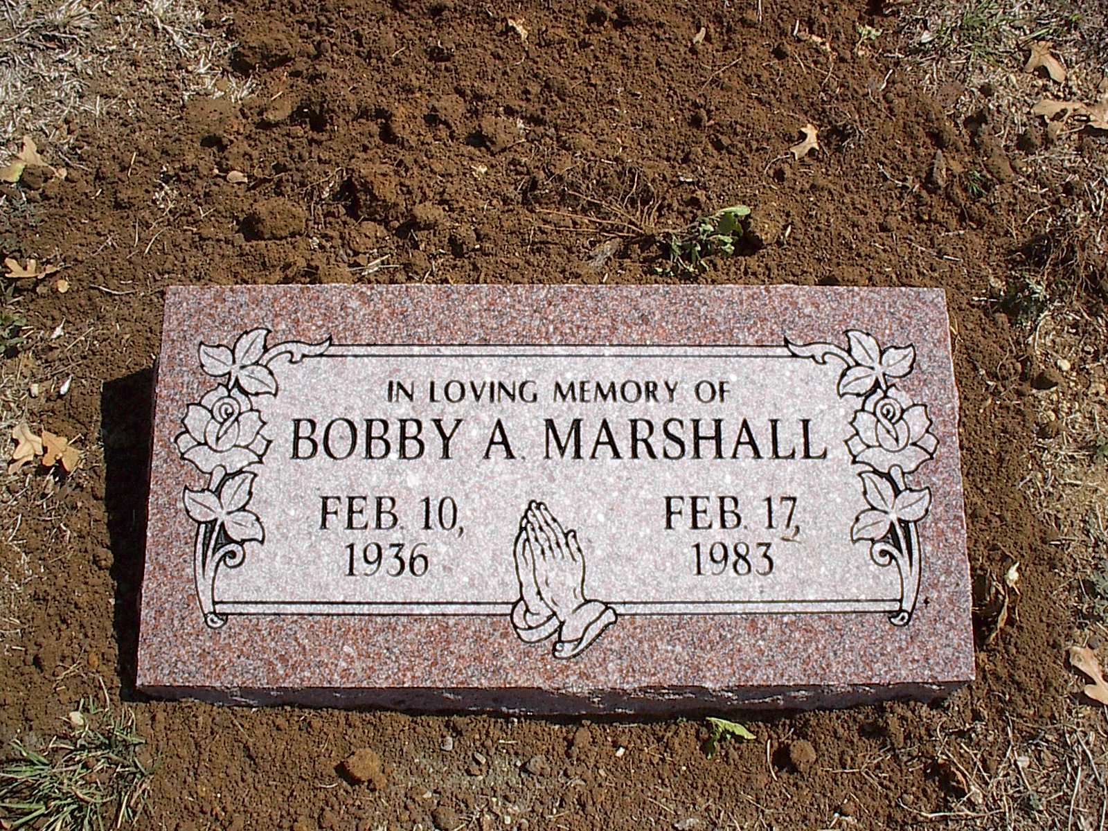 Gravestone of Bobby A. Marshall with dates Feb 10, 1936 - Feb 17, 1983, with praying hands and floral decorations.