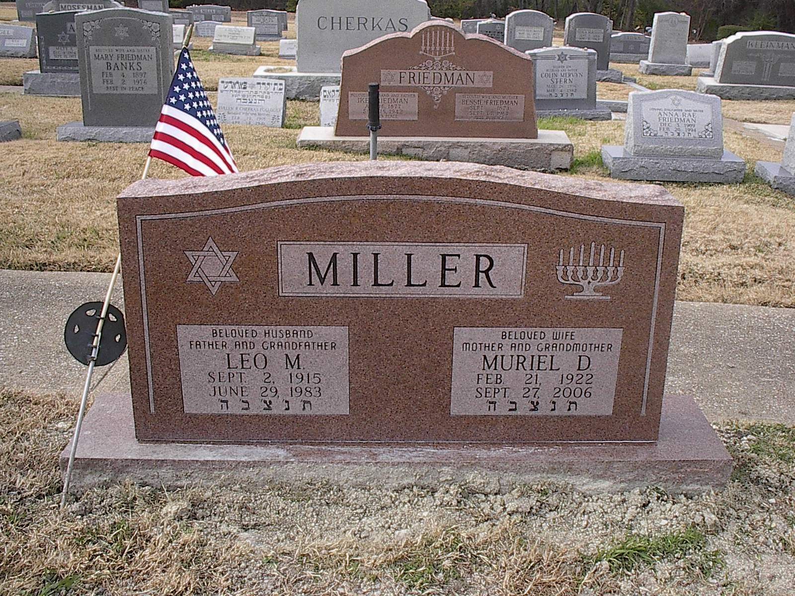 Red Miller family tombstone in a cemetery with an American flag.