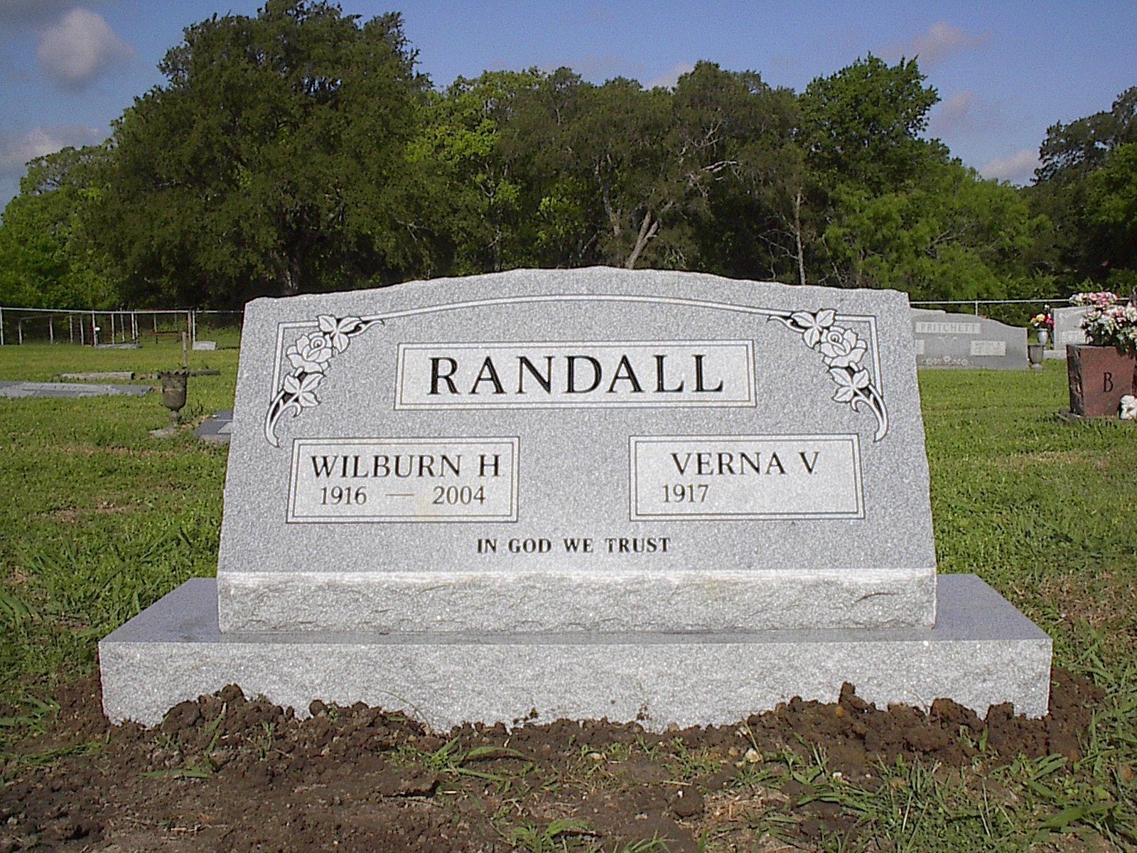Gray granite headstone in a cemetery; reads