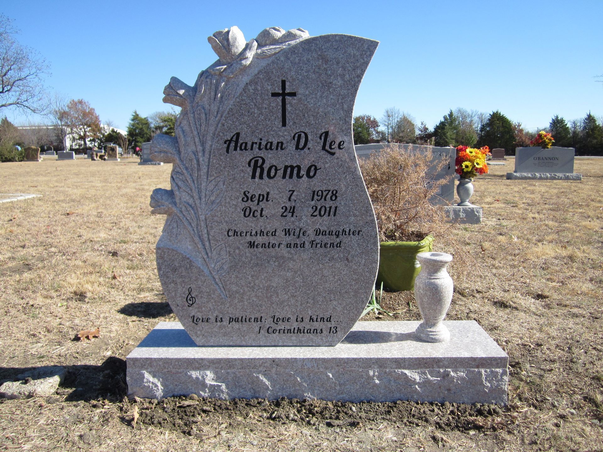 Grave marker for Marion Lee Romo, with cross and floral design, dates Sept. 1, 1918 - Oct. 29, 2001, in a cemetery.