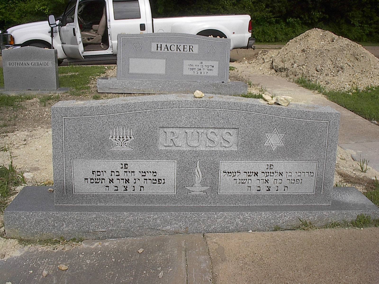 Gray headstones in a cemetery; one with the name