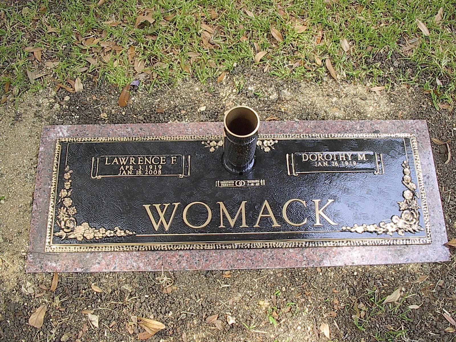 Bronze Womack headstone with flower vase in a grassy setting.
