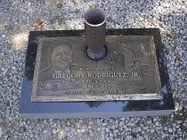 Bronze grave marker with a portrait and inscription, including a metal vase.