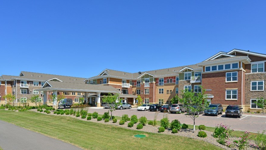 A large apartment building with cars parked in front of it.