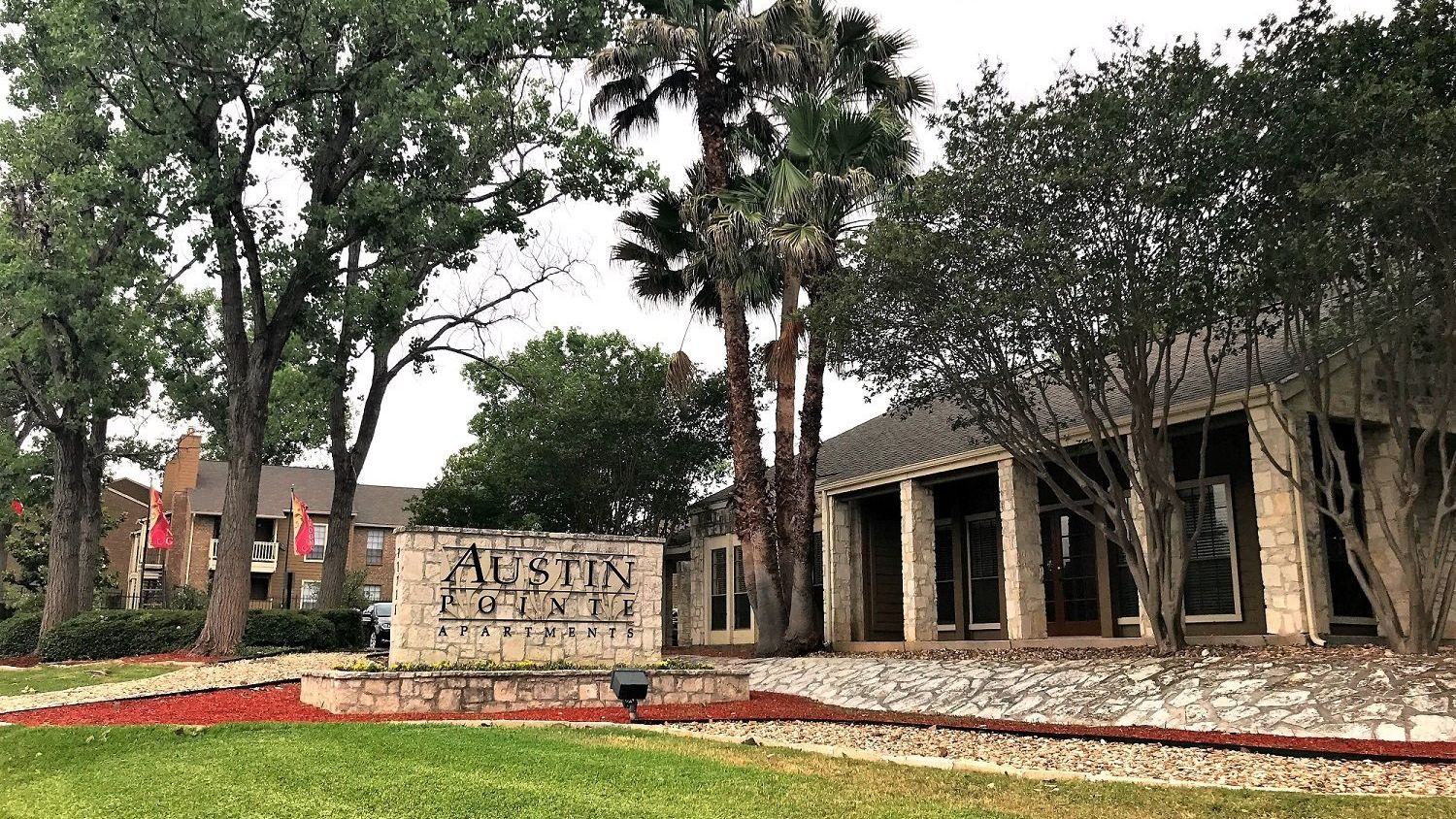 A building with a sign in front of it and trees in the background.
