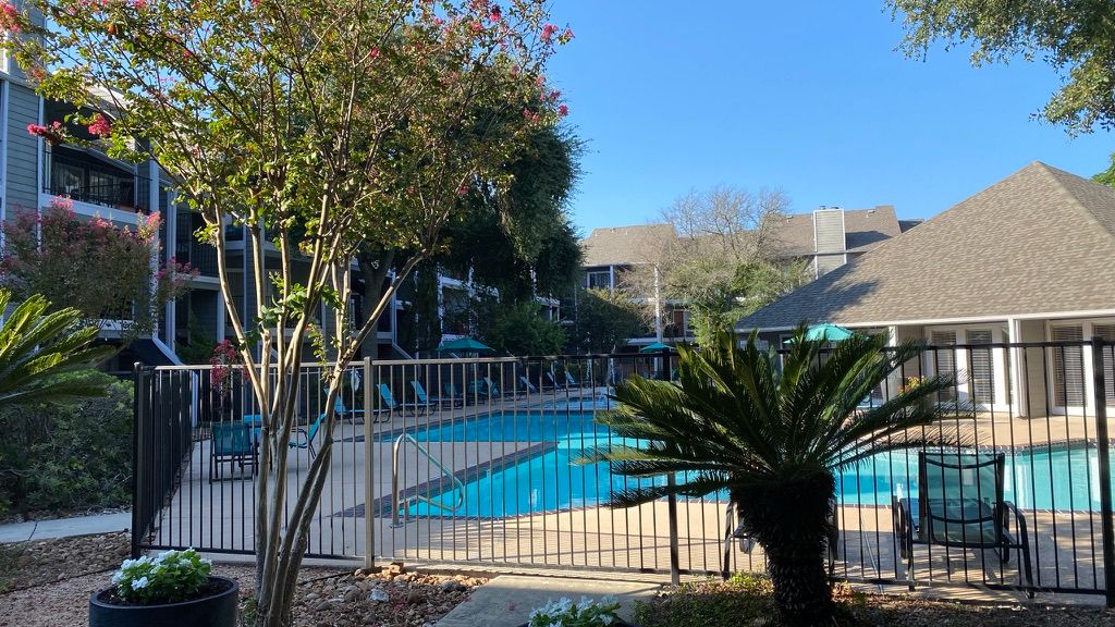 A large swimming pool surrounded by a fence in a residential area.