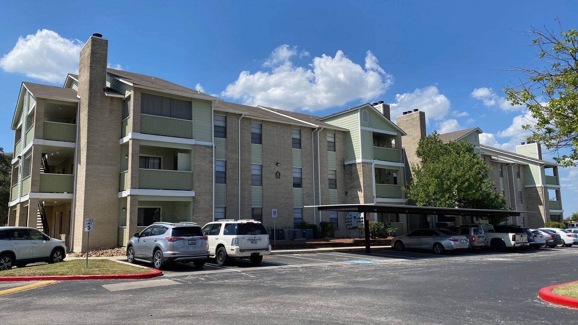 A large apartment building with cars parked in front of it.