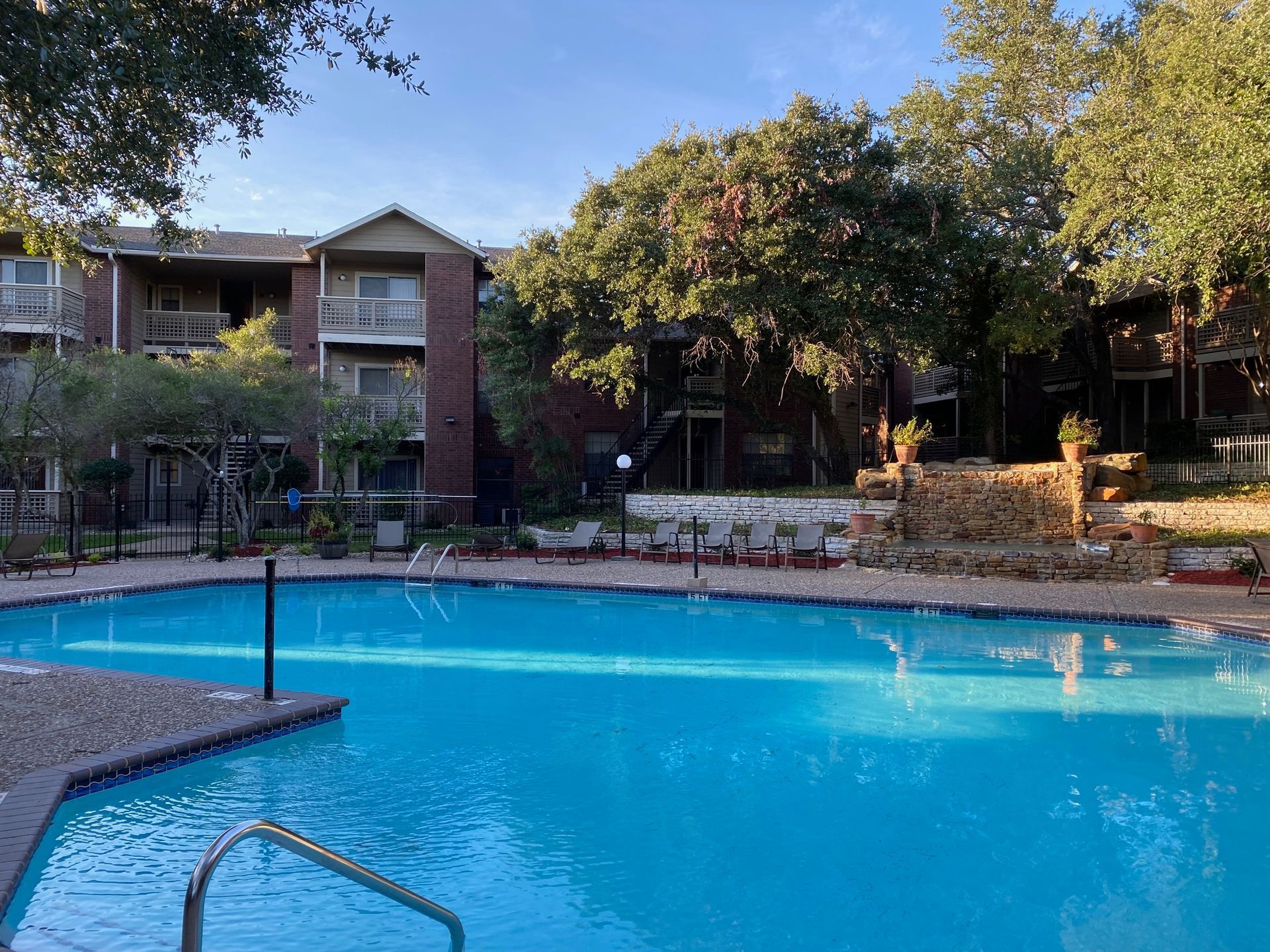 A large swimming pool in front of a building with stairs leading to it.