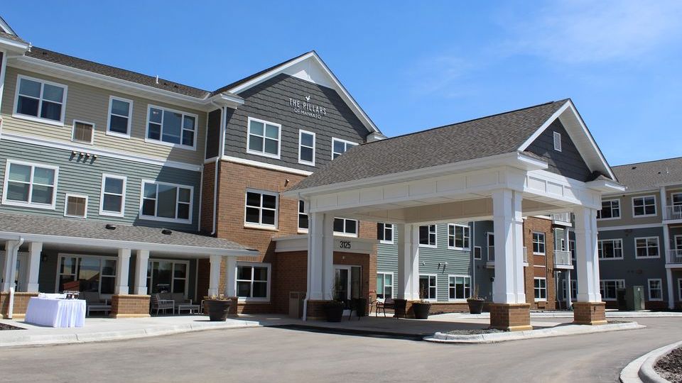 A large apartment building with a large porch and a blue sky in the background.
