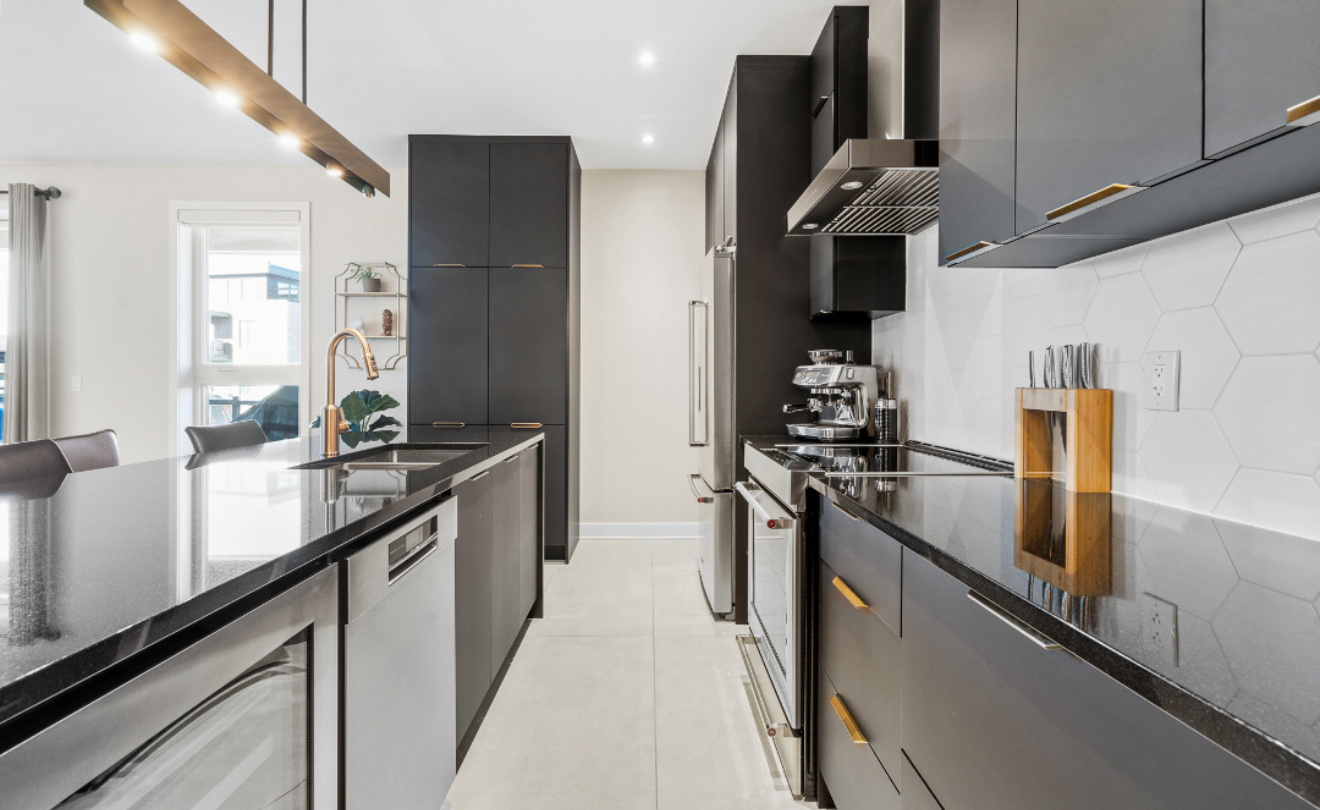 Cuisine moderne en longueur avec armoires gris foncé, comptoirs blancs et électroménagers en acier inoxydable