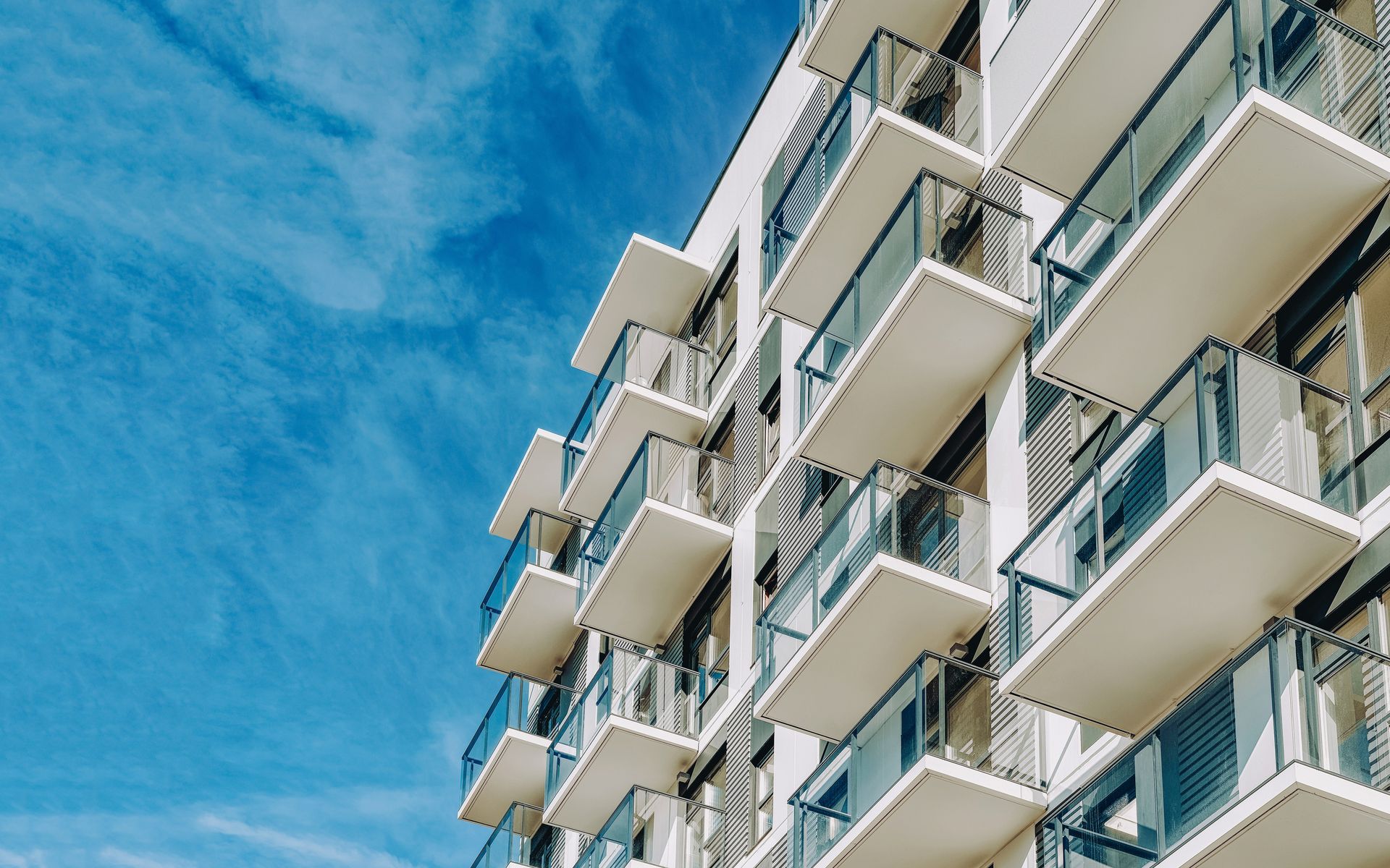 Immeuble d'appartements moderne avec des balcons blancs se détachant sur un ciel bleu