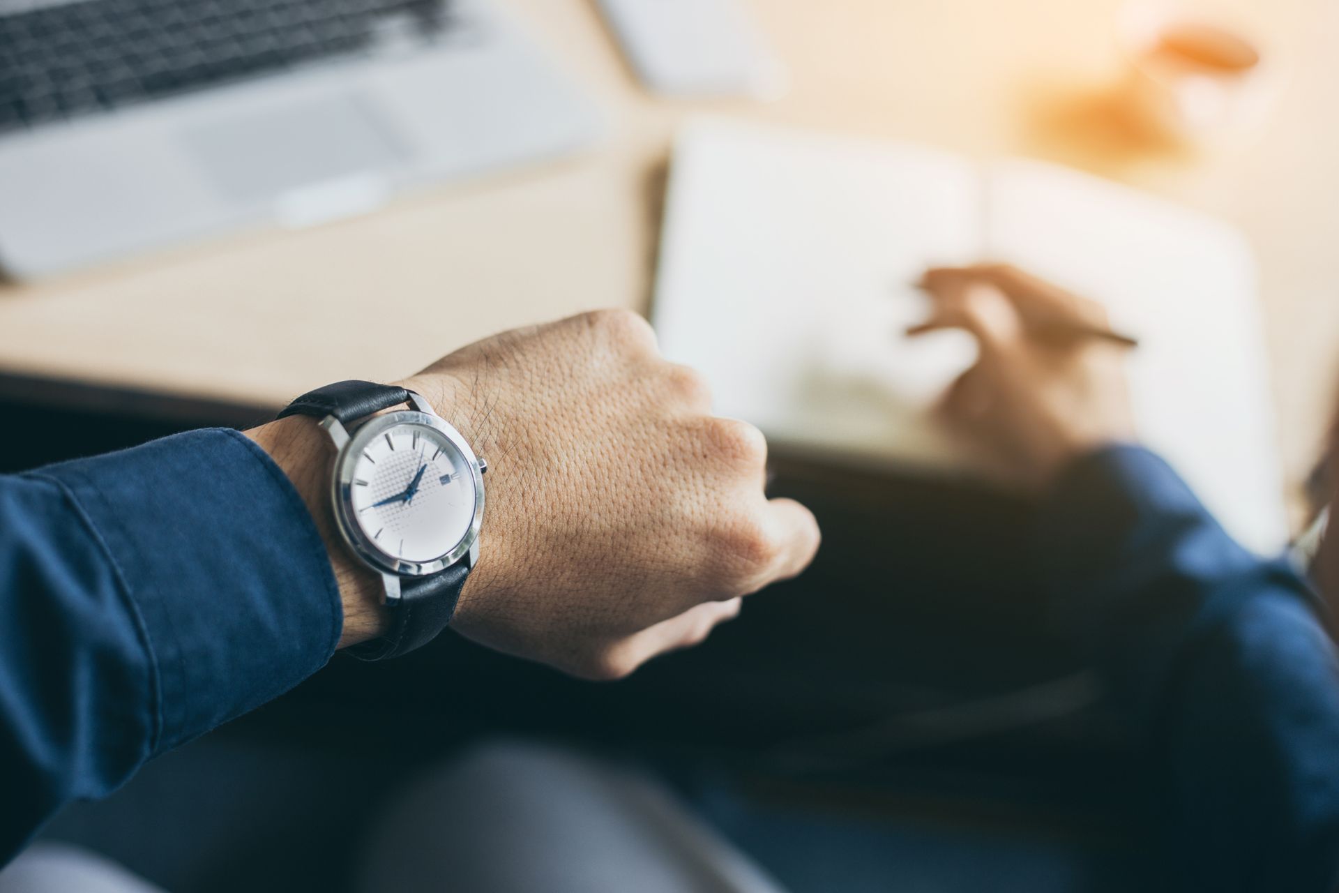 Gros plan sur une montre-bracelet portée au bras, avec une personne floue allongée sur un canapé en arrière-plan.