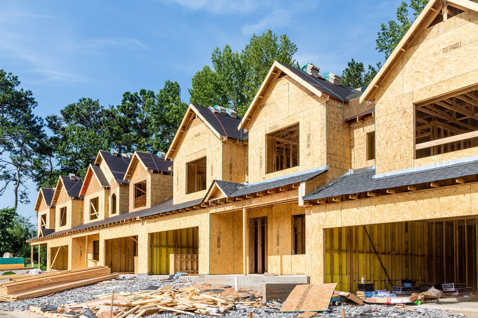 Rang&eacute;e de maisons neuves en construction avec ossature bois et bardage en cours de finition.