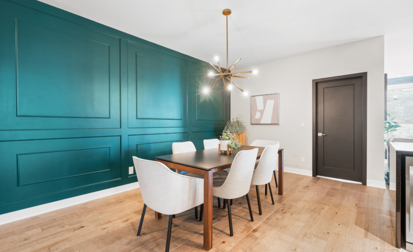 Salle à manger moderne avec un mur d'accent turquoise, une table en bois, des chaises blanches et une suspension dorée.
