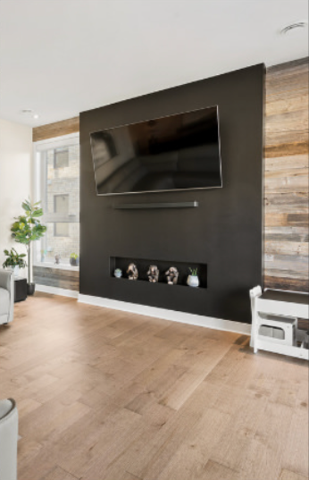 Salon moderne avec télévision murale, mur d'accent noir et parquet clair