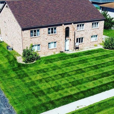 An aerial view of a brick house with a lush green lawn in front of it.