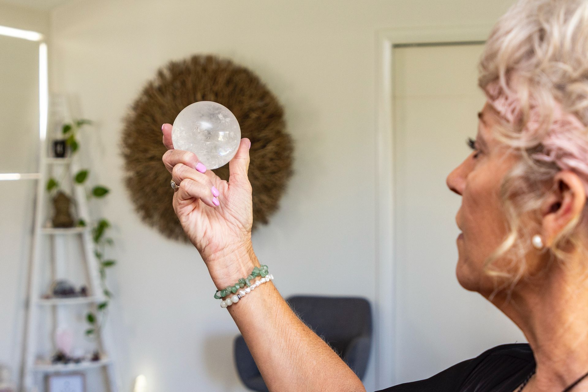 Woman holding a round compact mirror while looking at her reflection in a bedroom. — Soulfully Happy In Springvale, NSW