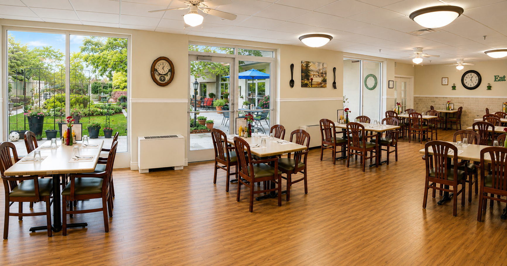Bright dining hall with wooden tables, chairs, and large windows overlooking greenery