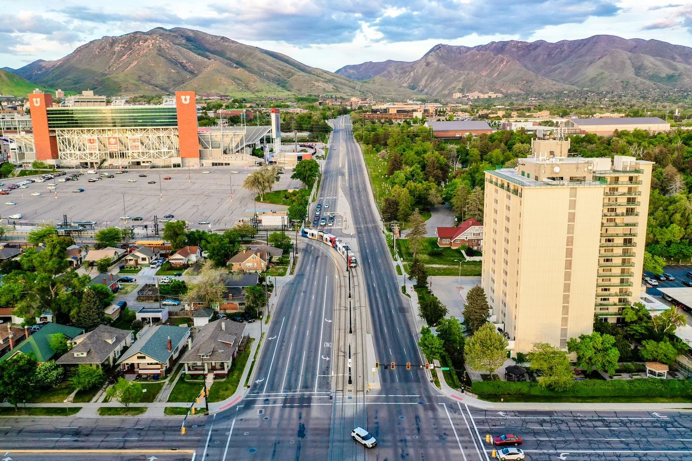 Aerial view of a wide city street with mountains in the background and buildings on both sides.