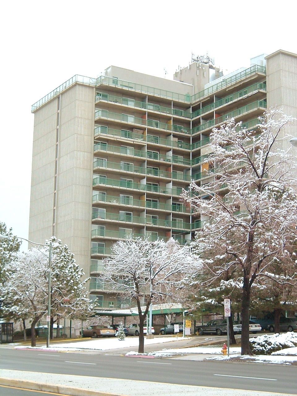 Snowy apartment building with bare trees lining the street