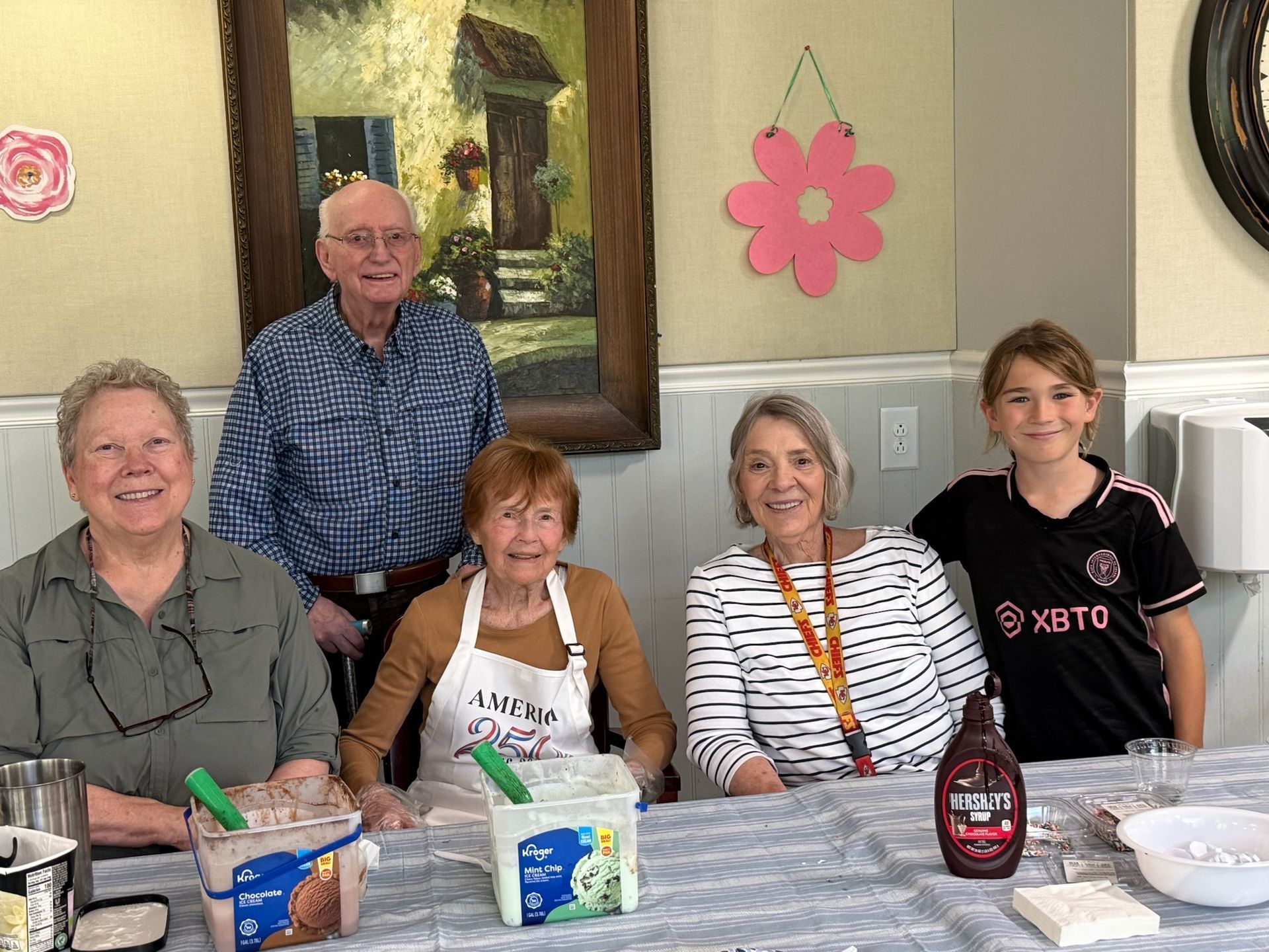 Five people seated at a table in a dining room, smiling with food and drinks in front of them