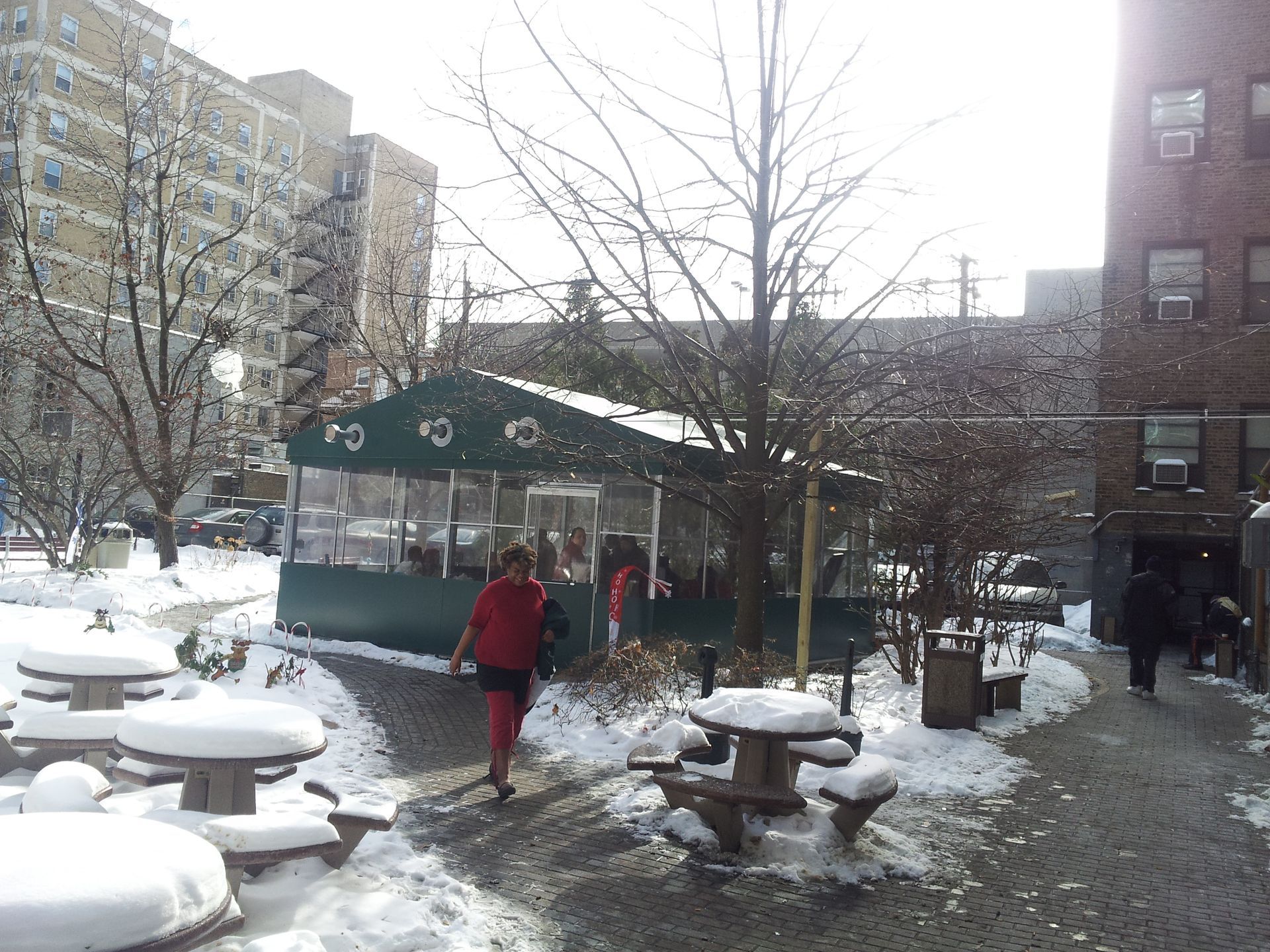 A woman walking in the snow near a building