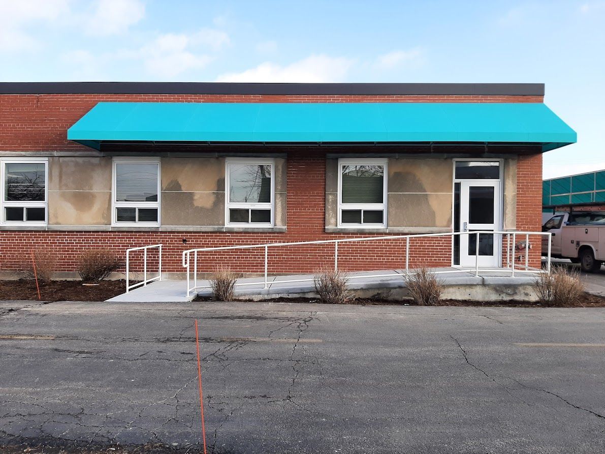 A brick building with a blue awning and a ramp