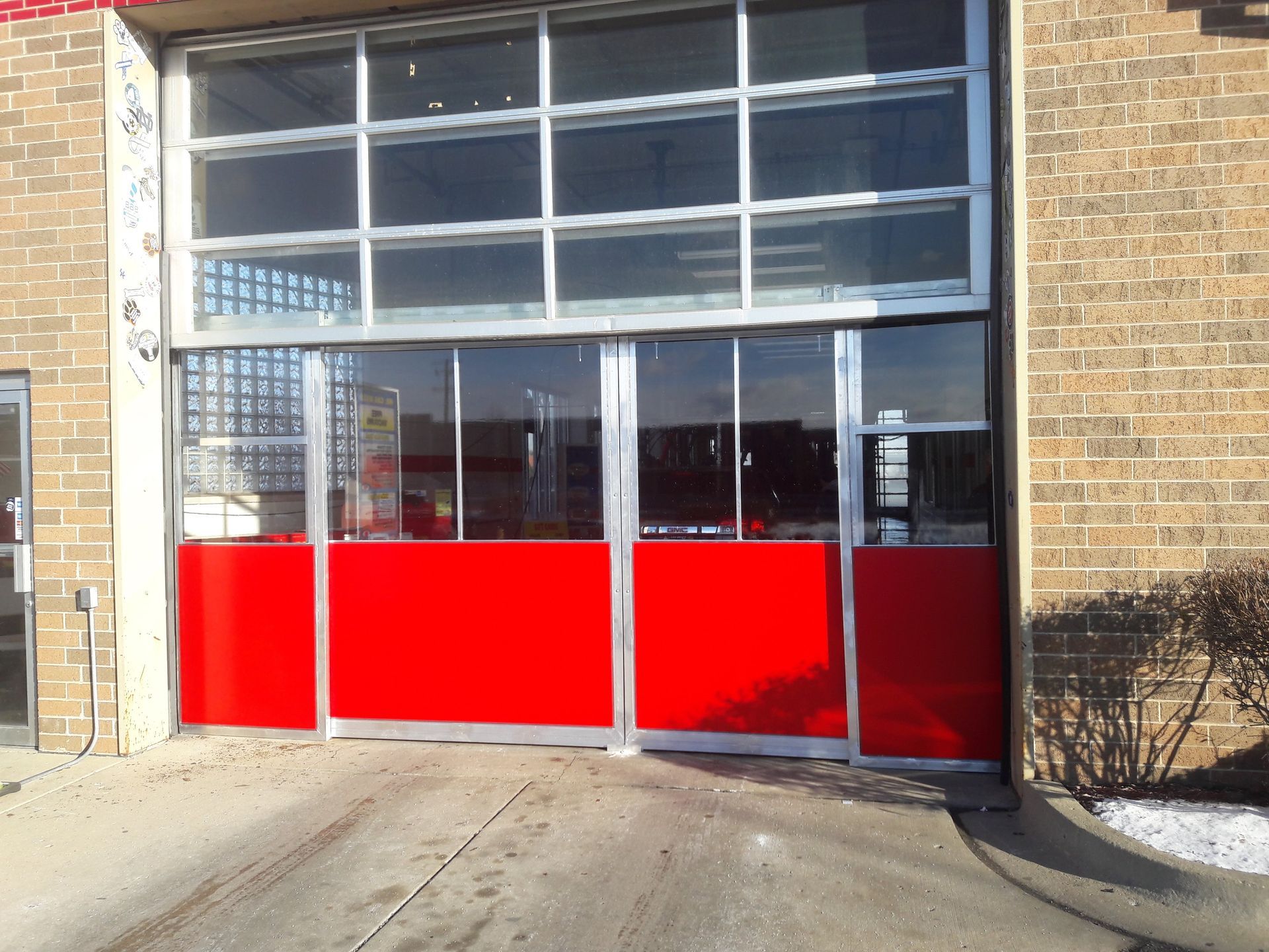 A red garage door with a brick building in the background