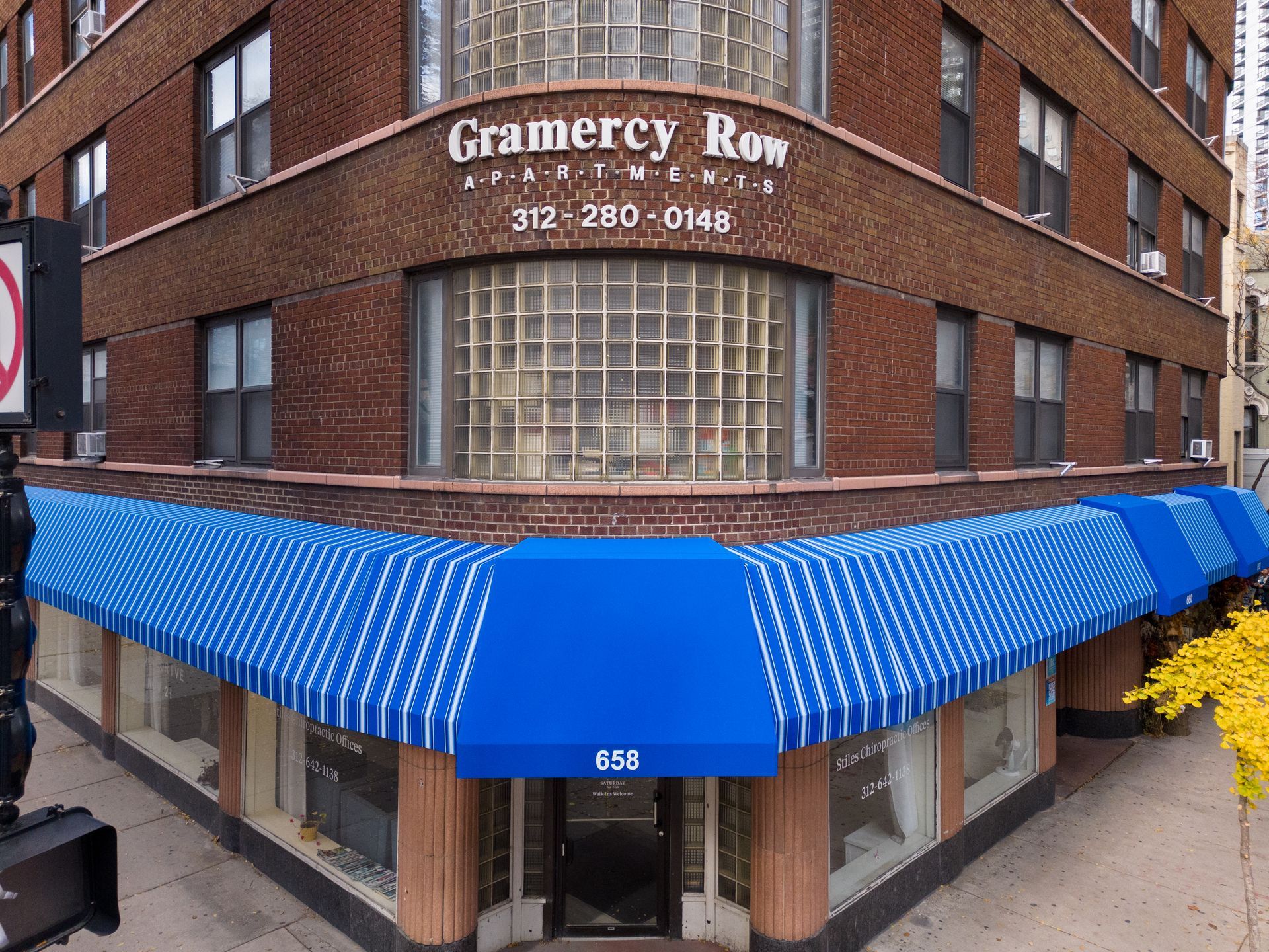 A brick building with a blue awning on the corner