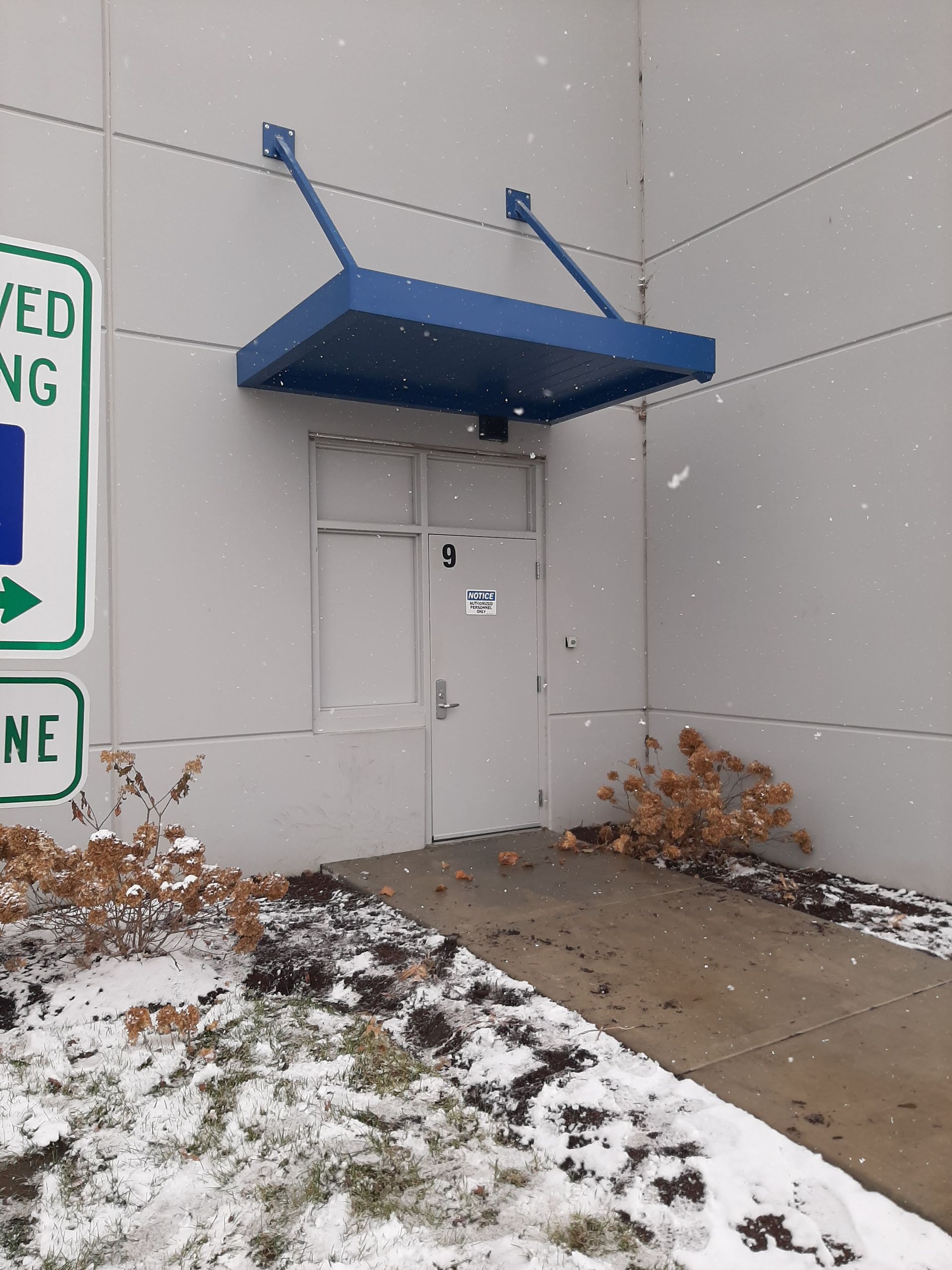 A white building with a blue canopy over the door