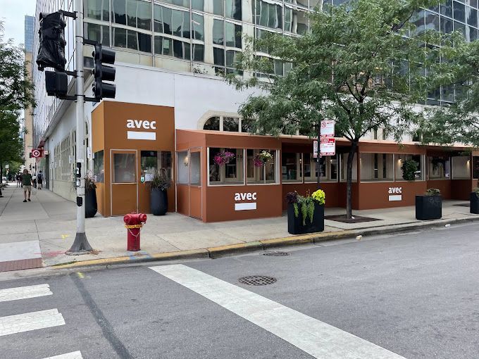 A restaurant called avec is on the corner of a city street