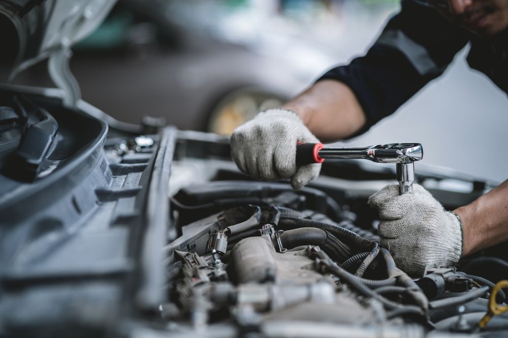 A Man is Working on a Car Engine With a Wrench — Bowral Auto Care In Mittagong, NSW