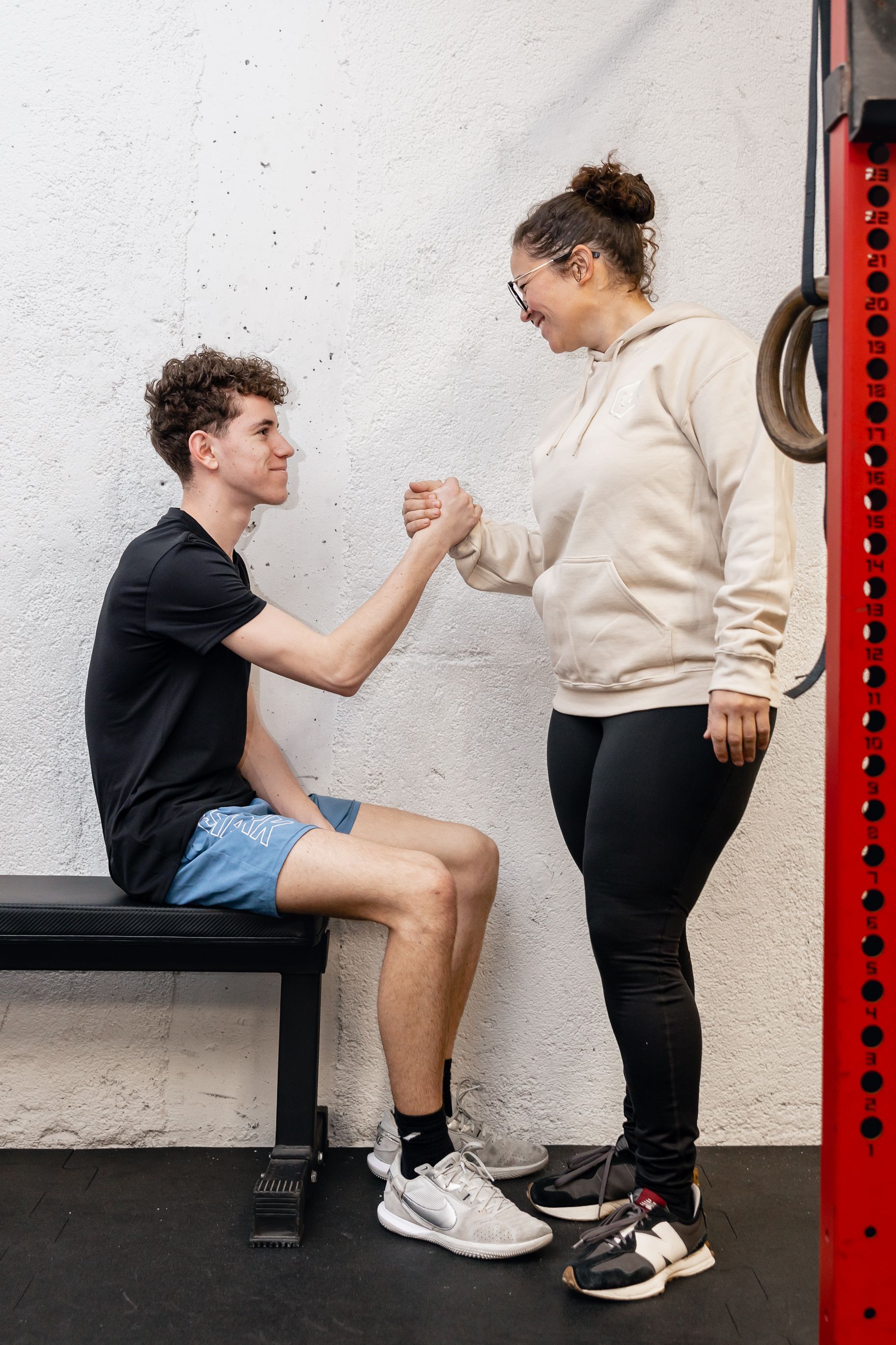 Trainer assisting person doing crunches on a blue floor in a gym.